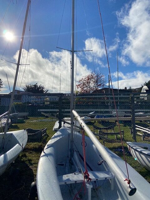 A 420 sail boat before it gets rigged with sails, while the sun is shining down from very blue skies.